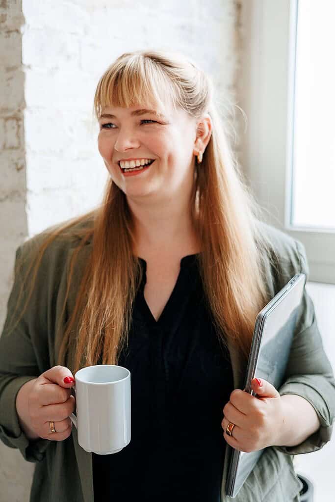 Fröhliche Frau mit Tasse und Smartphone, beruhigend, Elternmagnet, Elternmarketing, positive Stimmung.