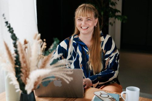 Fröhliche Frau arbeitet an Laptop, Elternmagnet, Mutti, flexible Arbeitsmodelle, Homeoffice, Elternschaft, digitale Marketingstrategien, harmonievolle Work-Life-Balance.
